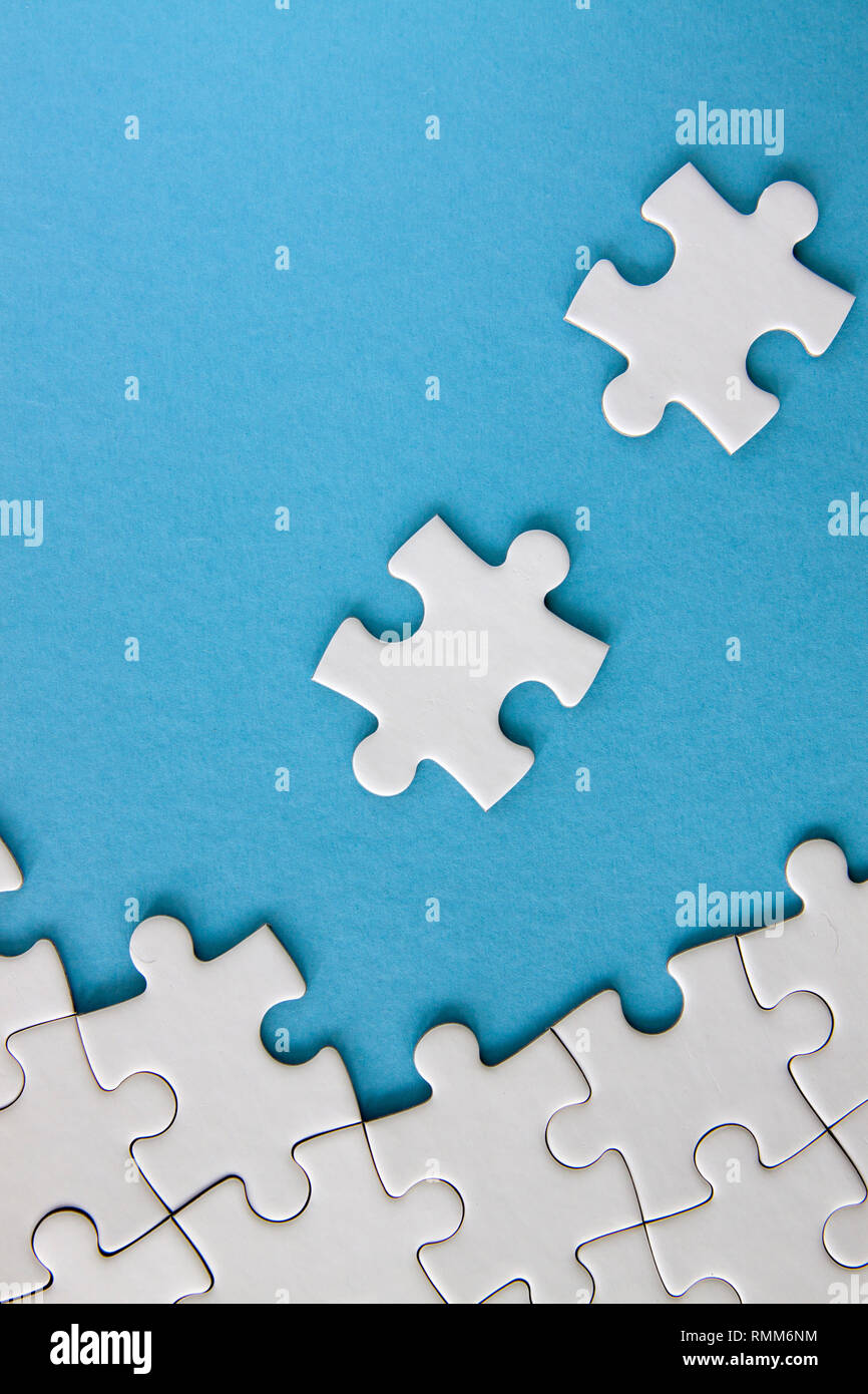 White jigsaw puzzle pieces on blue background Stock Photo