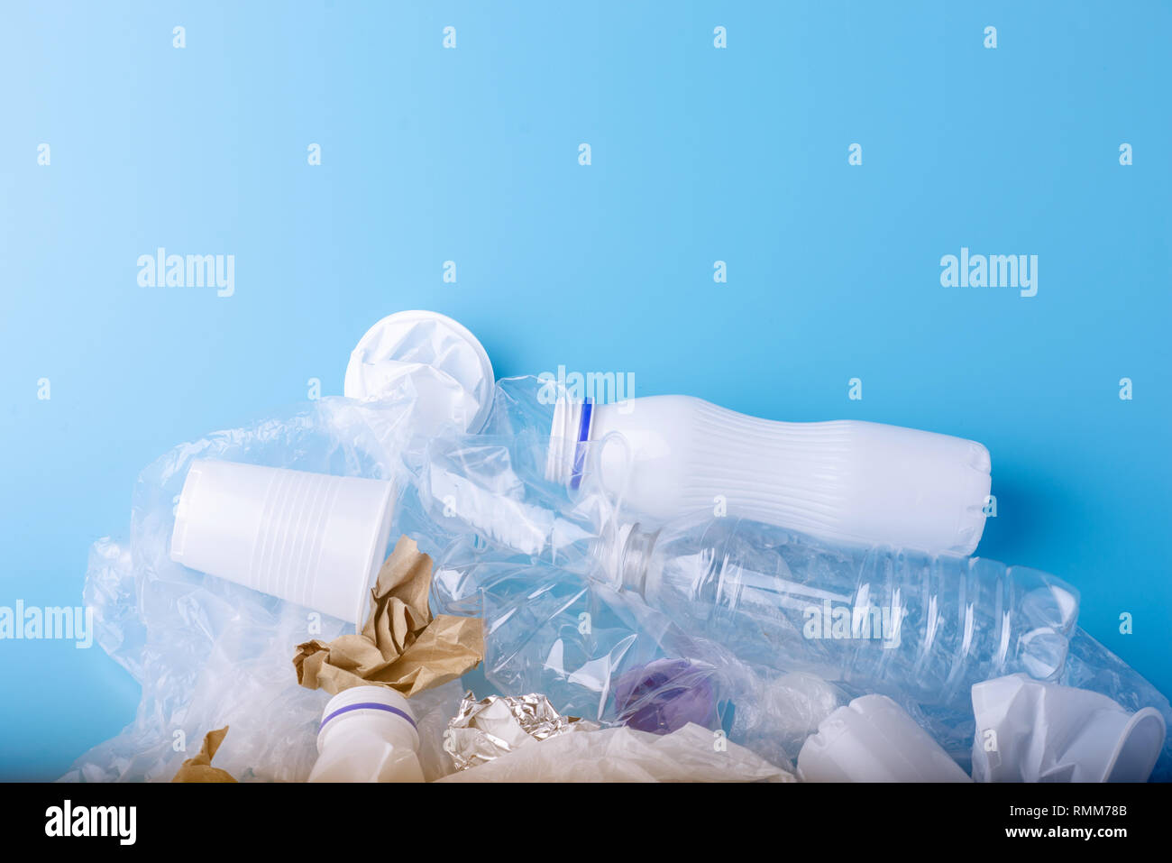 Used unsorted clean garbage in a pile. Bottles, bags and paper on blue background. Concept of environmental pollution and waste sorting Stock Photo