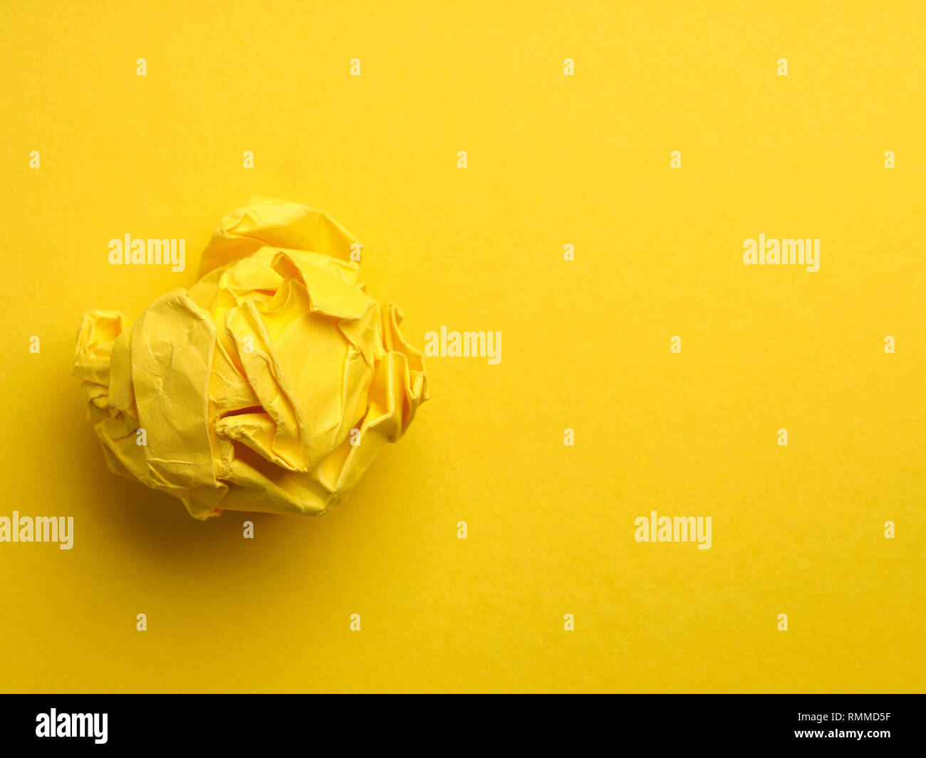 Crumpled yellow paper ball on a yellow background with space for text or image, view from above Stock Photo