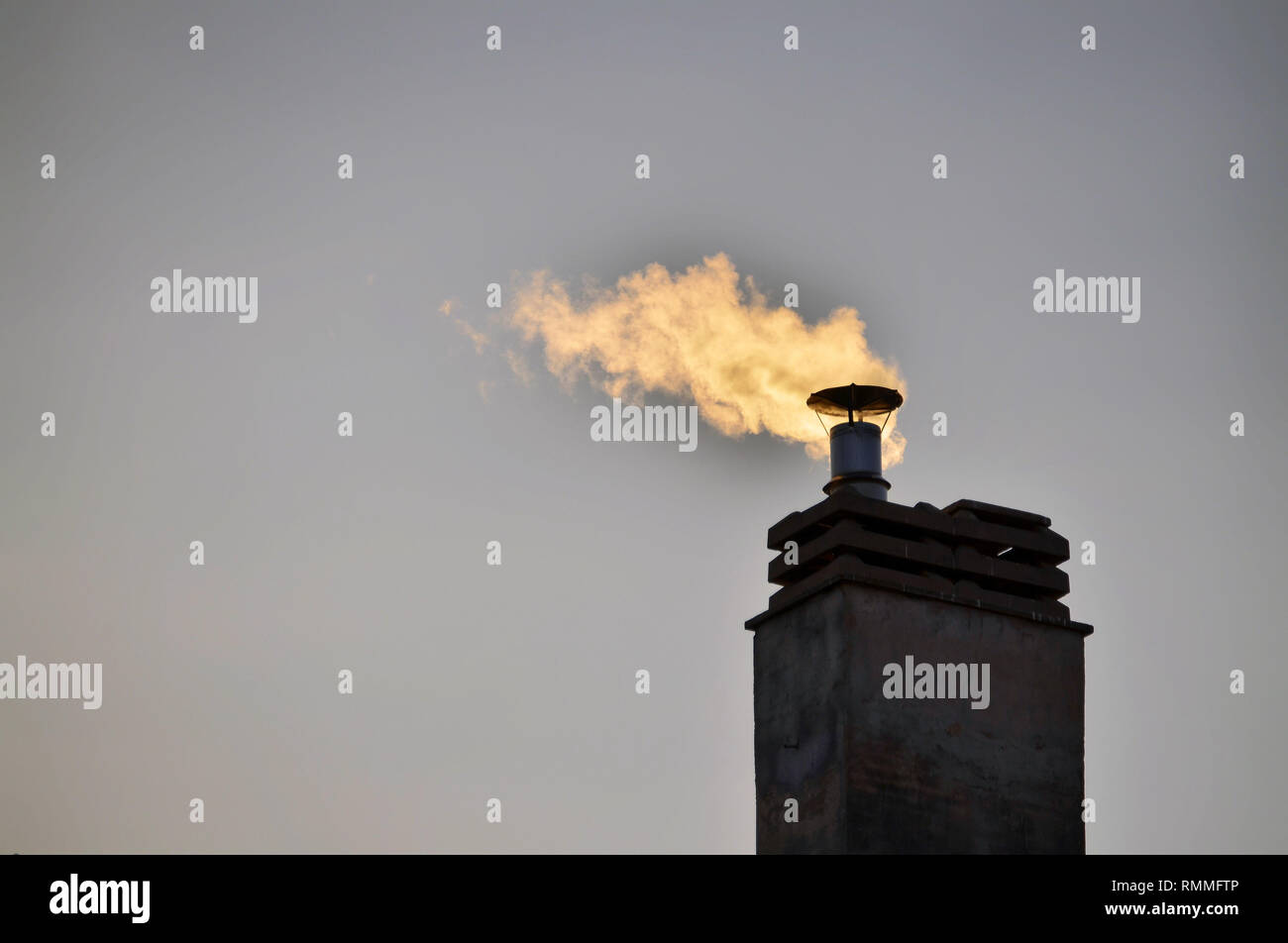 Chimney of a condominium heating system. The winter sun rays at sunset ...