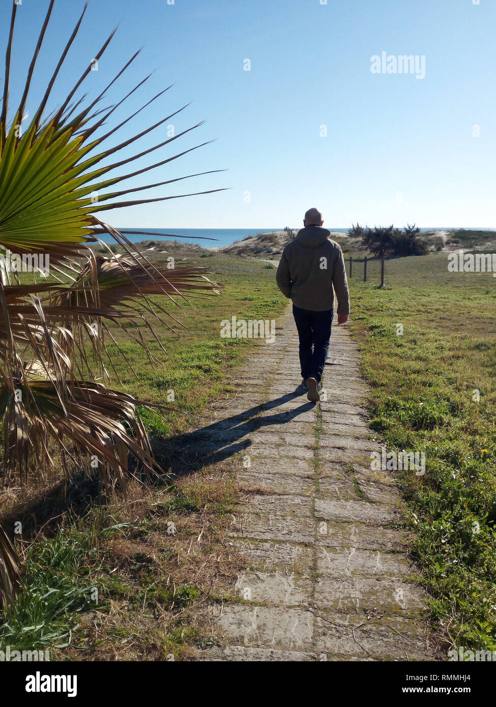 Man walking along a footpath towards the sea, Italy Stock Photo
