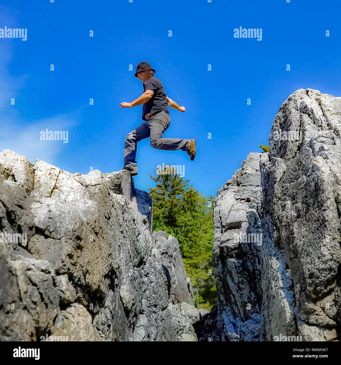 Man jumping across rocks, Canada Stock Photo Alamy