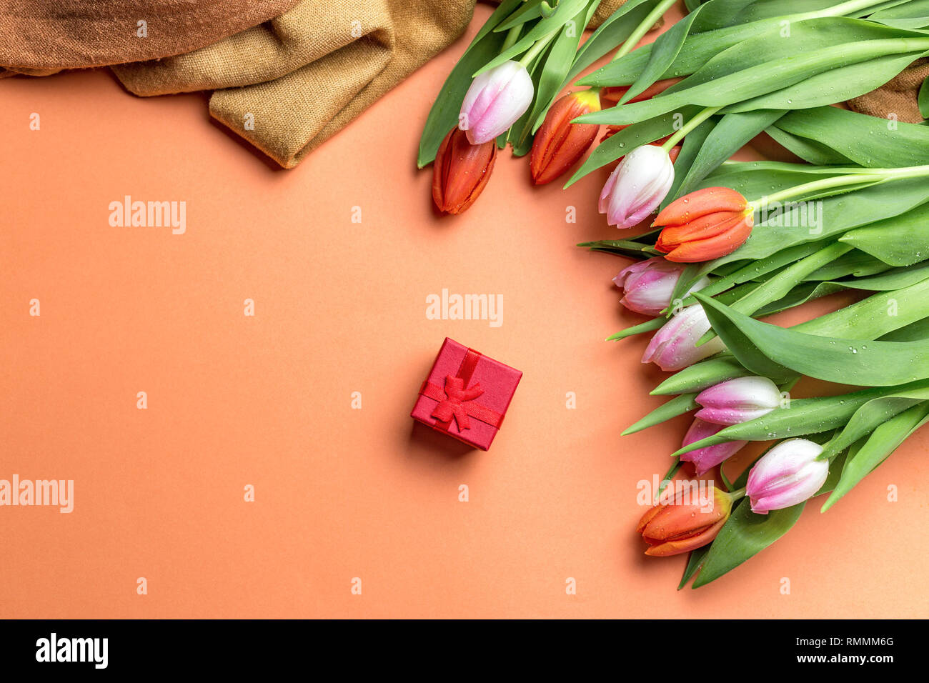 Fresh pink tulips on a table, top view. Tulips on the table and red gift with place for text Stock Photo