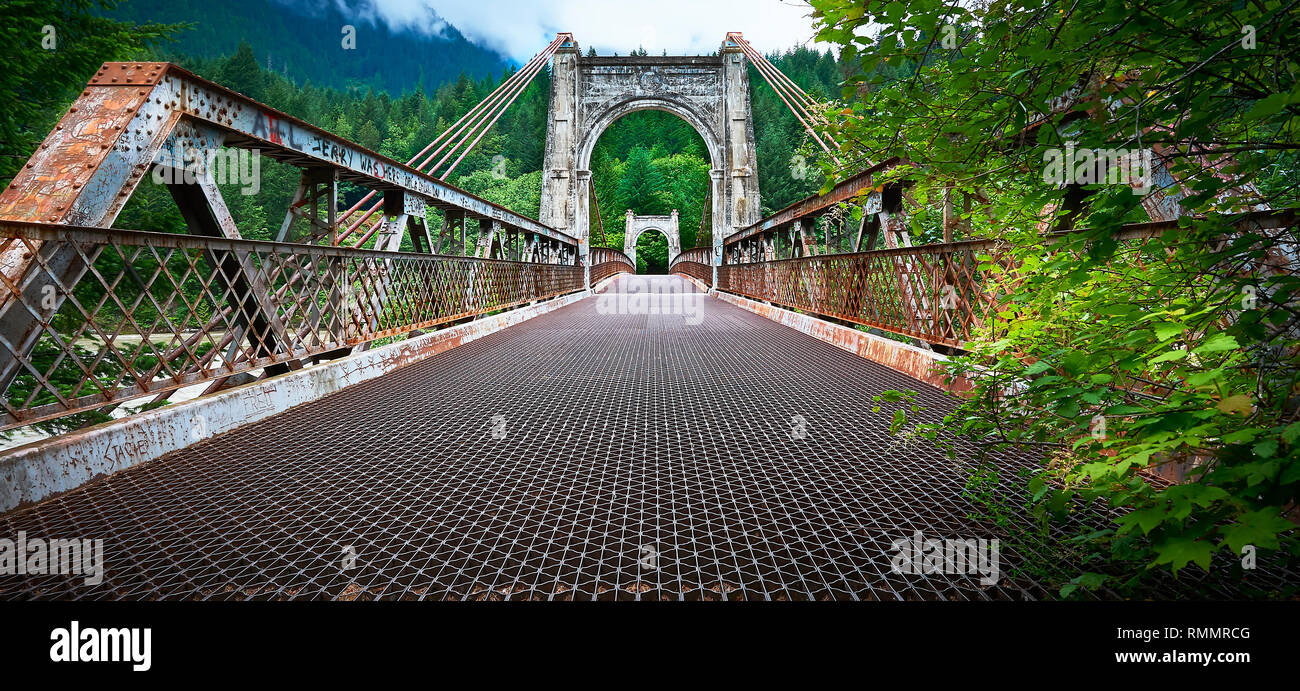Lillooet, B.C., Canada - June 30, 2012: Low angle view of a rusty metal suspension bridge over the Fraser river Stock Photo