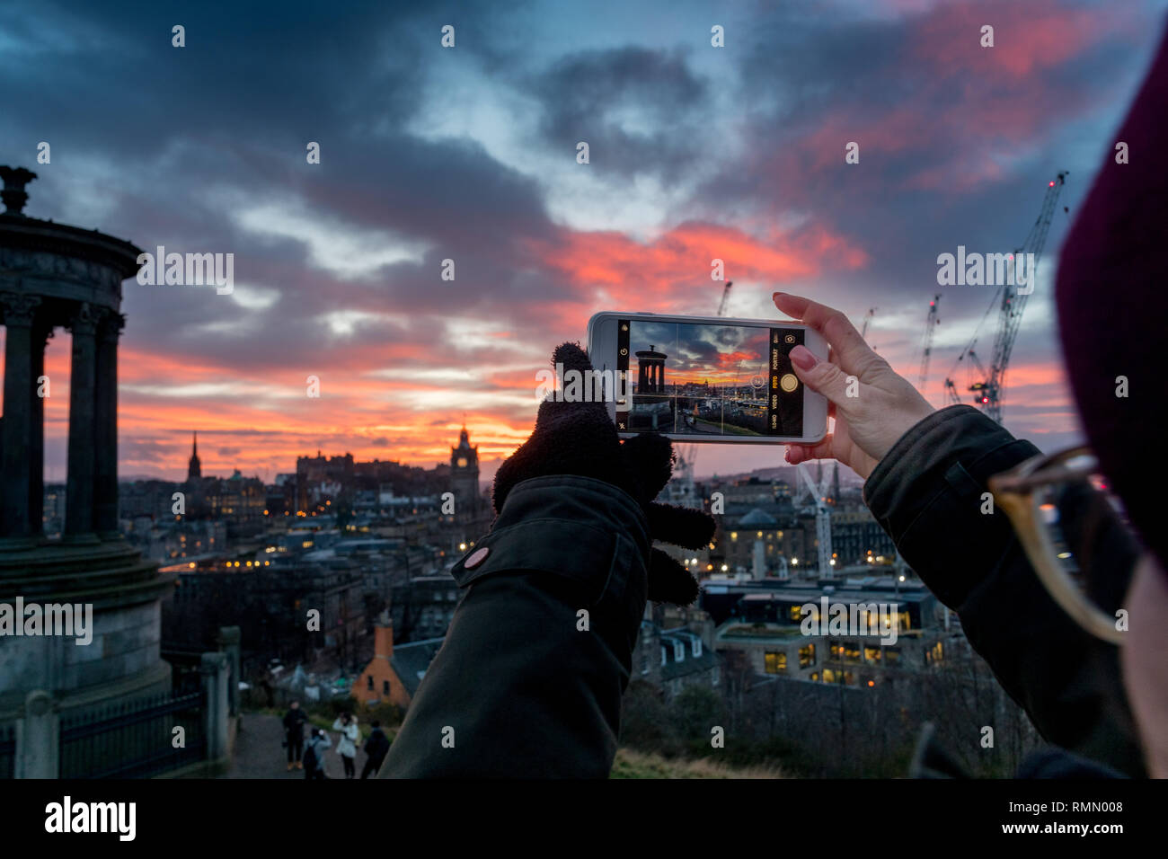 smartphone photographer over the City of Edinburgh at sunset Stock Photo