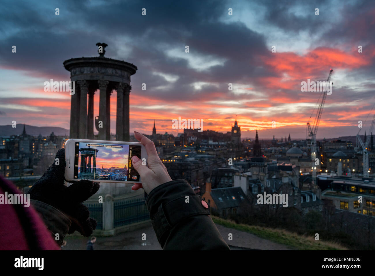 smartphone photographer over the City of Edinburgh at sunset Stock Photo