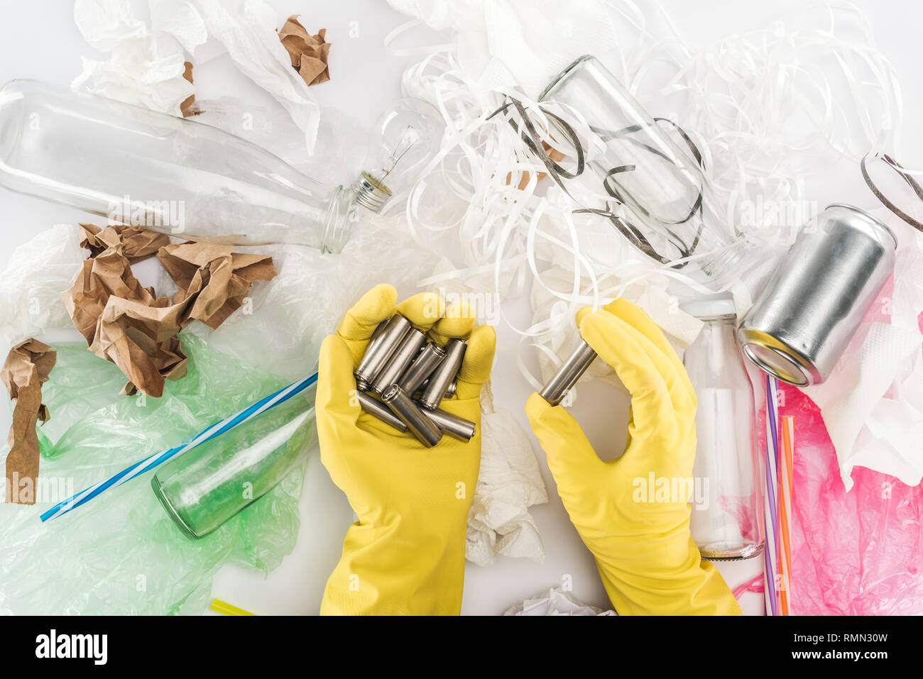 Partial view of man holding batteries among can, glass bottles, plastic