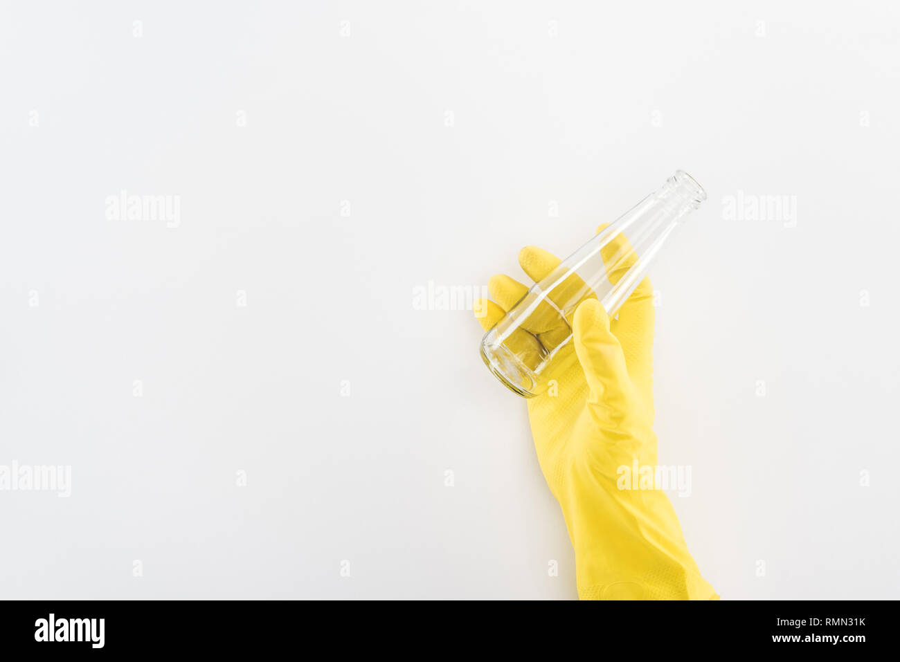 Partial view of man in yellow rubber gloves holding empty glass bottle ...