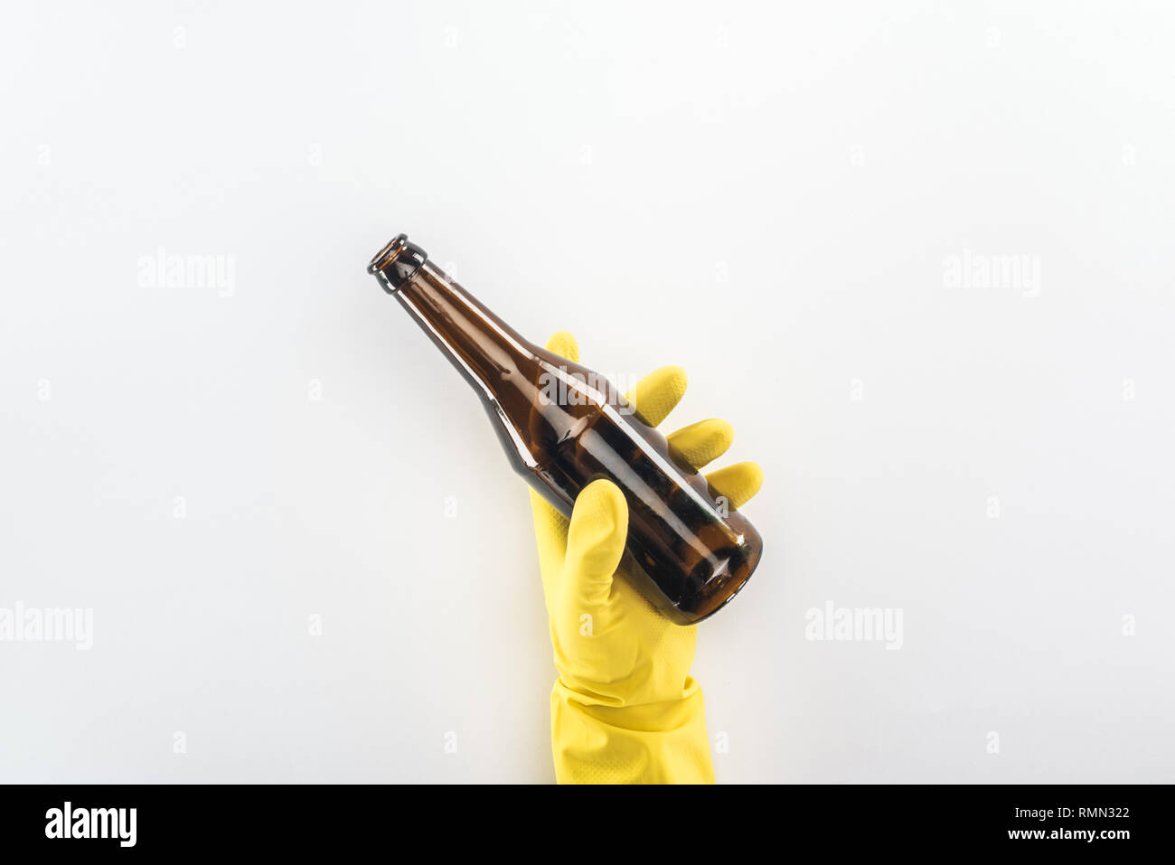 Cropped view of man in yellow rubber gloves holding empty glass bottle ...