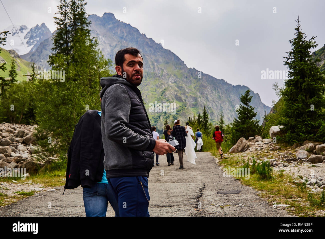 EDITORIAL, 02/08/2018 / Kyrgyzstan Ala-Archa gorge. An adult male tourist climbs the mountain road with a small group of people. Stock Photo