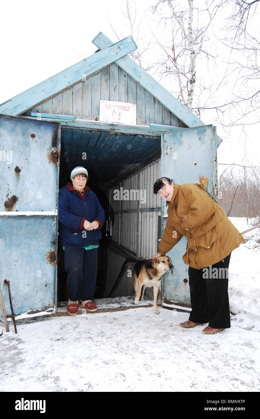 Galina Vasilievna seen waiting at the entrance to the ex-soviet bomb shelter with Alina Viktorovna encouraging the dog. The war between the Ukrainian army and the soldiers of the Donetsk Peoples Republic has cost the lives of 12,000 people and those who have been displaced exceed a million. It escalated in 2014. Despite a ceasefire in place, it is evident that death still occurs from predominantly, sniper, mortar and mines. The construction of trenches either side of no-man’s land, (often only 100mt apart) have ensured a static yet aggressive confrontation. The Minsk ceasefire agreement and co Stock Photo
