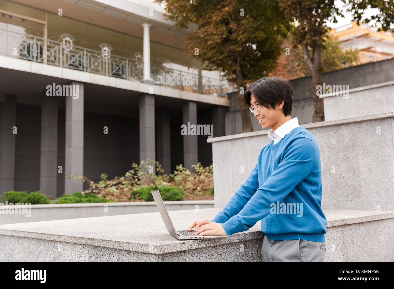 Smiling asian business man using laptop computer outdoors Stock Photo ...