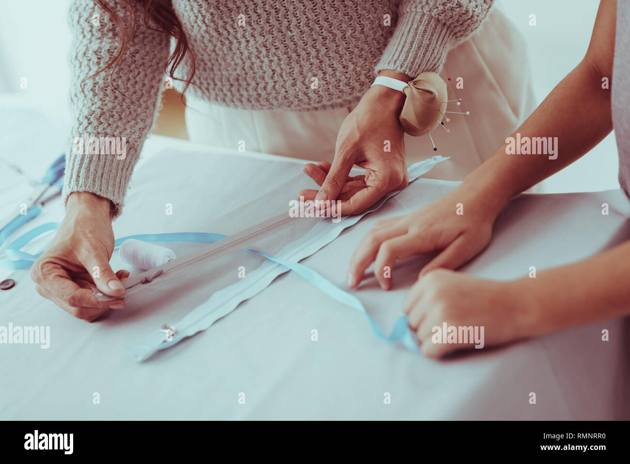 Best choice. Close up of hardworking family choosing a zipper for new dress while standing at the table Stock Photo