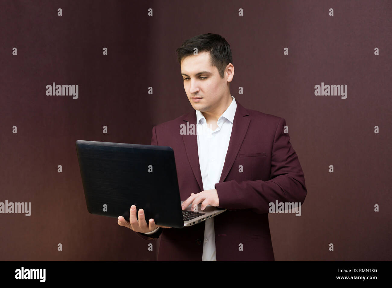 Handsome Man With Black Hair With A Computer In A Burgundy Suit