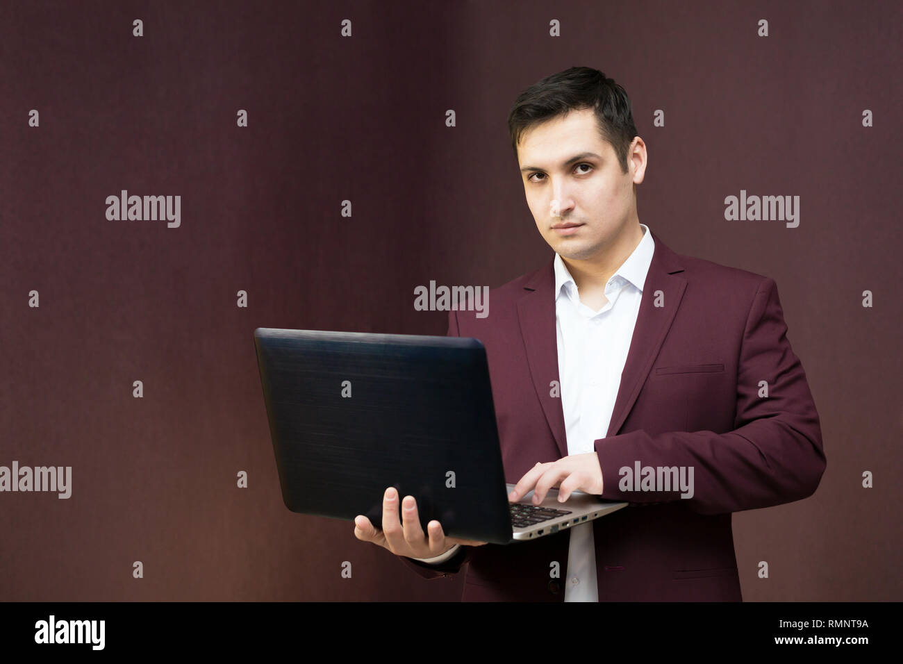 Handsome Man With Black Hair With A Computer In A Burgundy Suit