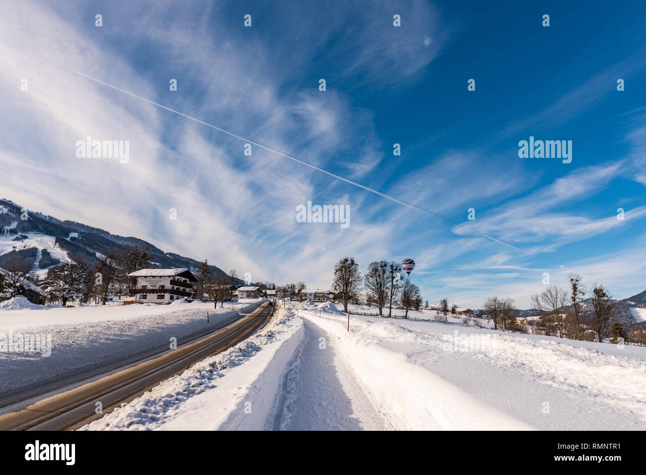Blue cloudy sky, big snow covered fields and empty road in winter, sunny day. Rohrmoos Untertal, Schladming, Schladming Dachstein, Austria, Europe Stock Photo