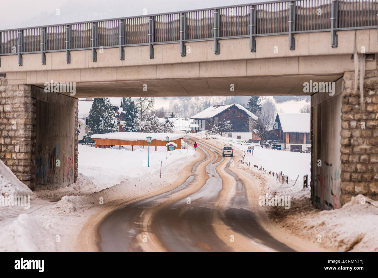 A winding road covered with snow, under the bridge. Dangerous drifts and ruts snow. Sunny day and snow all around. Styria, Austria, Europe Stock Photo
