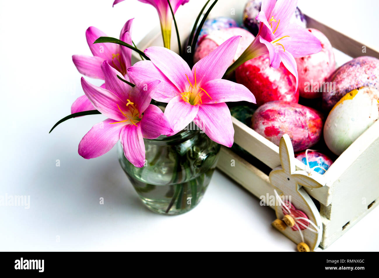 Pink lily flowers and Easter eggs in a basket on white Stock Photo - Alamy