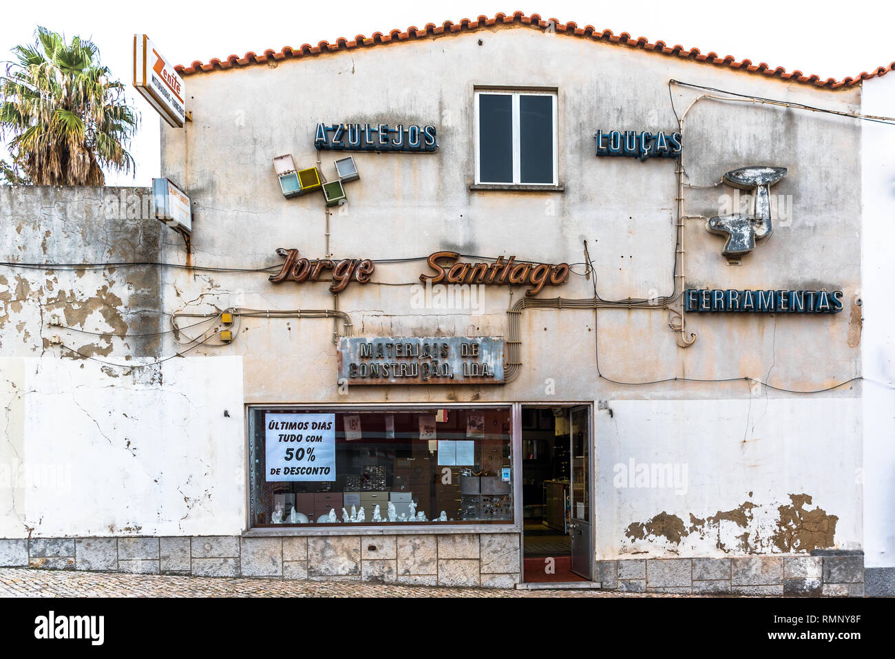 Cascais, Portugal - 6 December 2018: Hardware store front with multiple neon signs on facade advertising final days of closing-down sale in old town C Stock Photo