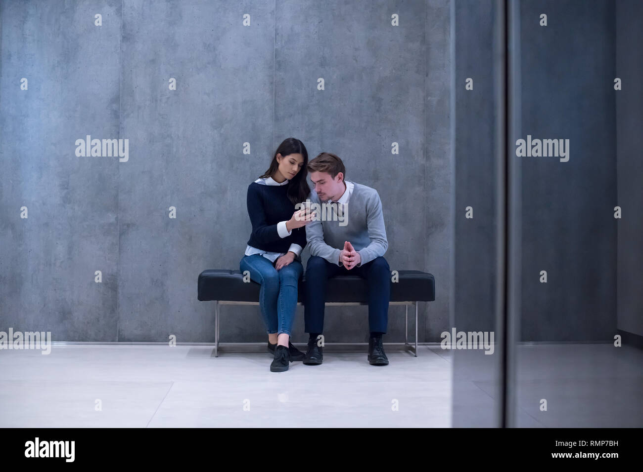 Young Business Couple Using Smart Phone While Sitting On The Bench