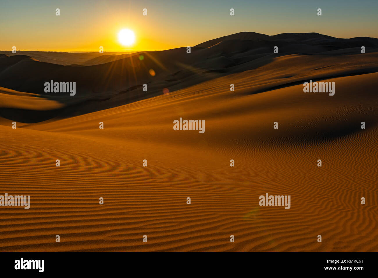 Sunset with lens flare and sand ripples in the foreground in the coast desert of Peru located between Ica, Huacachina and Nazca, south of Lima, Peru. Stock Photo