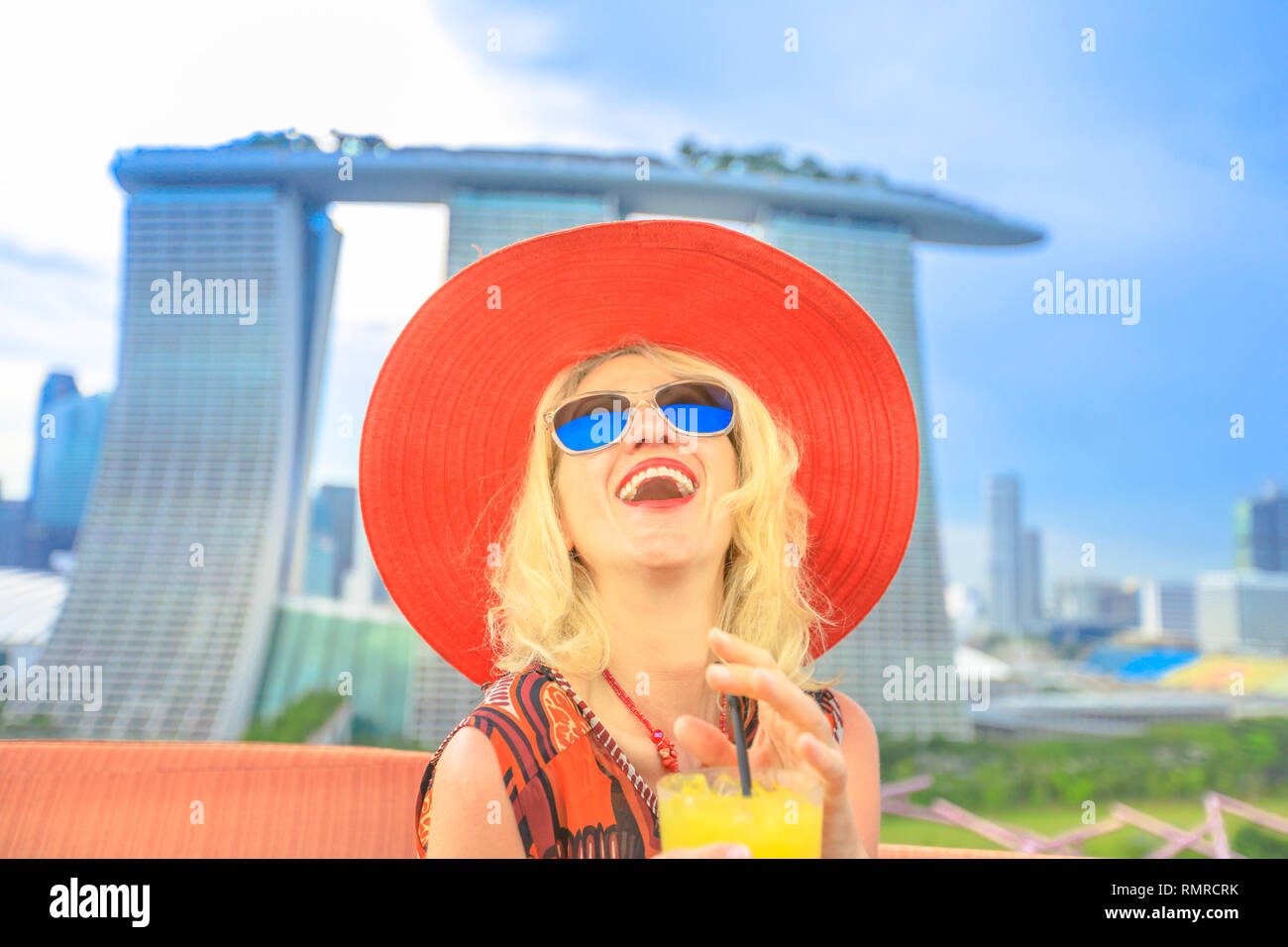 Happy tourist enjoying in travel holiday, Singapore, Southeast Asia. Lifestyle caucasian woman with wide hat drinking aperitif at rooftop. Aerial view Stock Photo