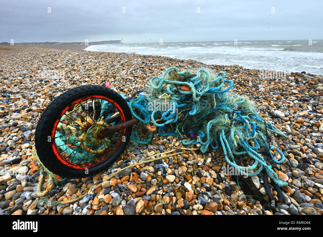 Old bike tangled in a plastic fishing net, discarded on a beach, East Sussex, UK Stock Photo