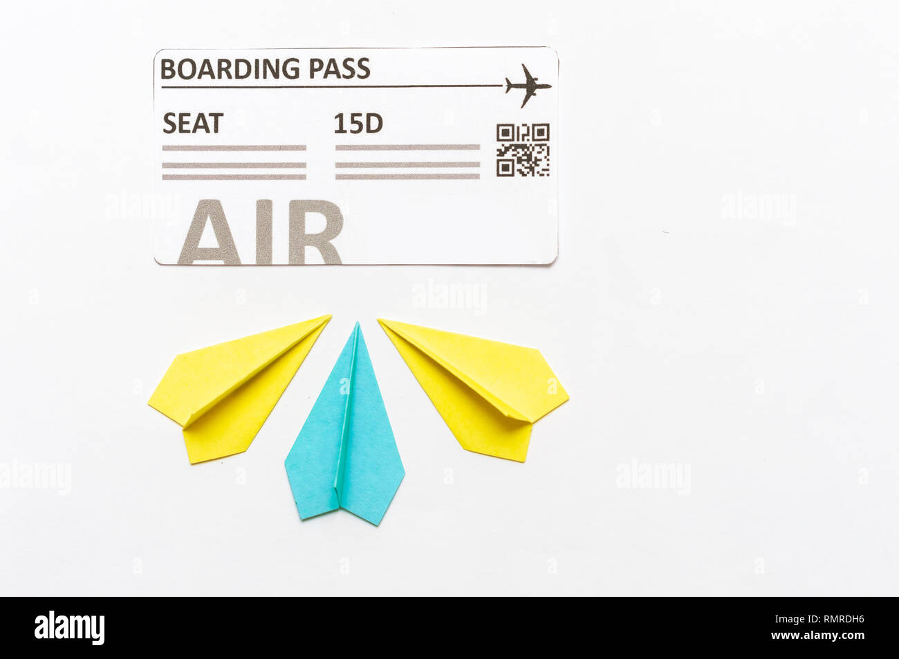 Differentiation concept in Aviation industry. Boarding pass and little paper airplanes, one blue, two yellow Stock Photo