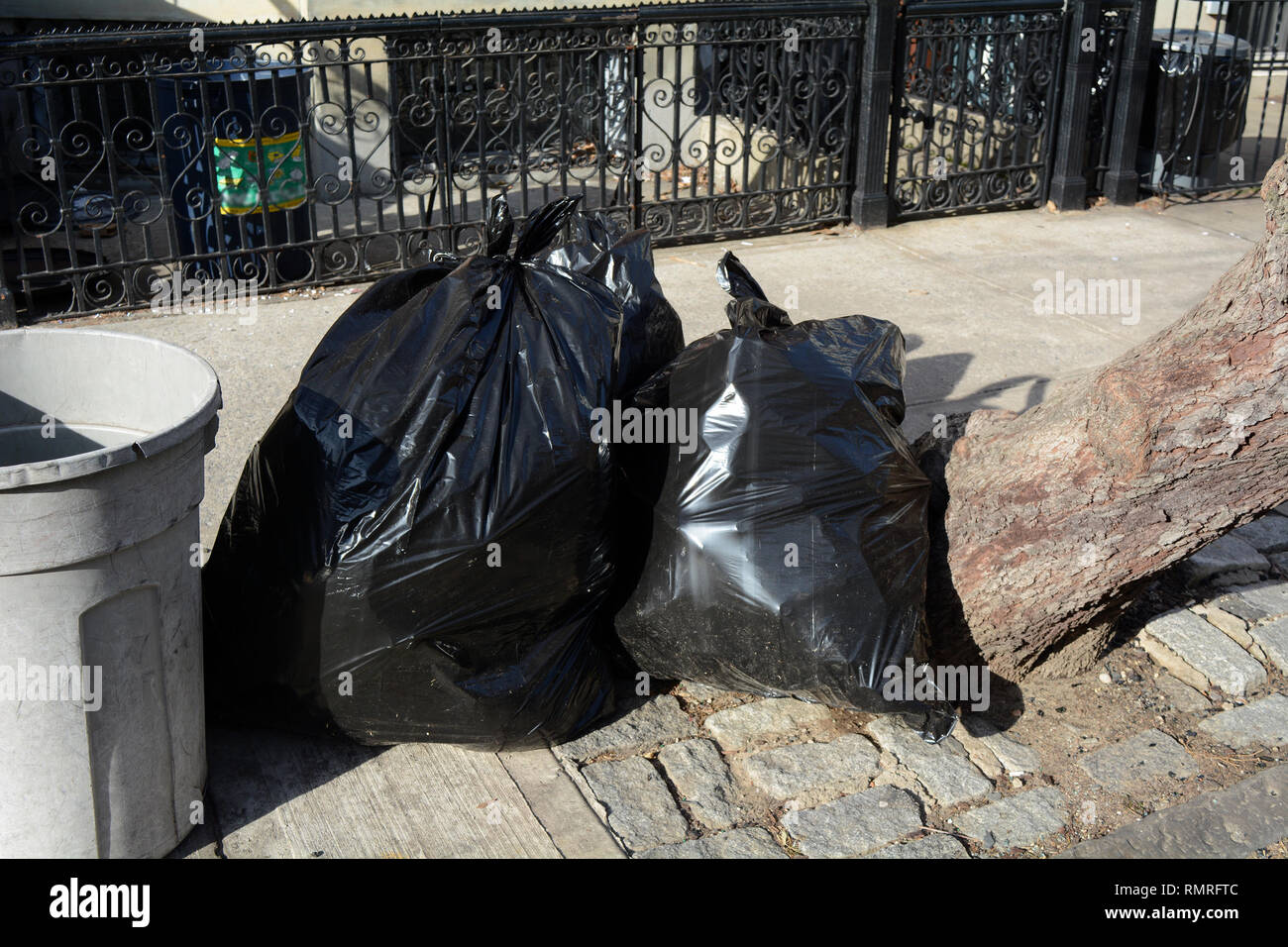 Garbage in Black Bags at Curb In City Stock Photo
