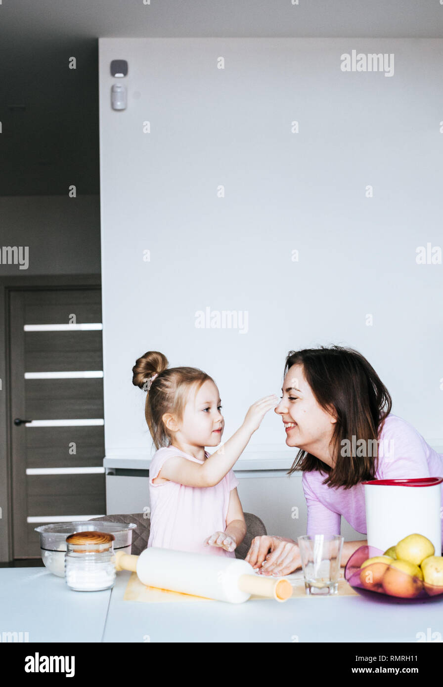 A mother and her daughter busy baking at home in the kitchen and having fun Stock Photo