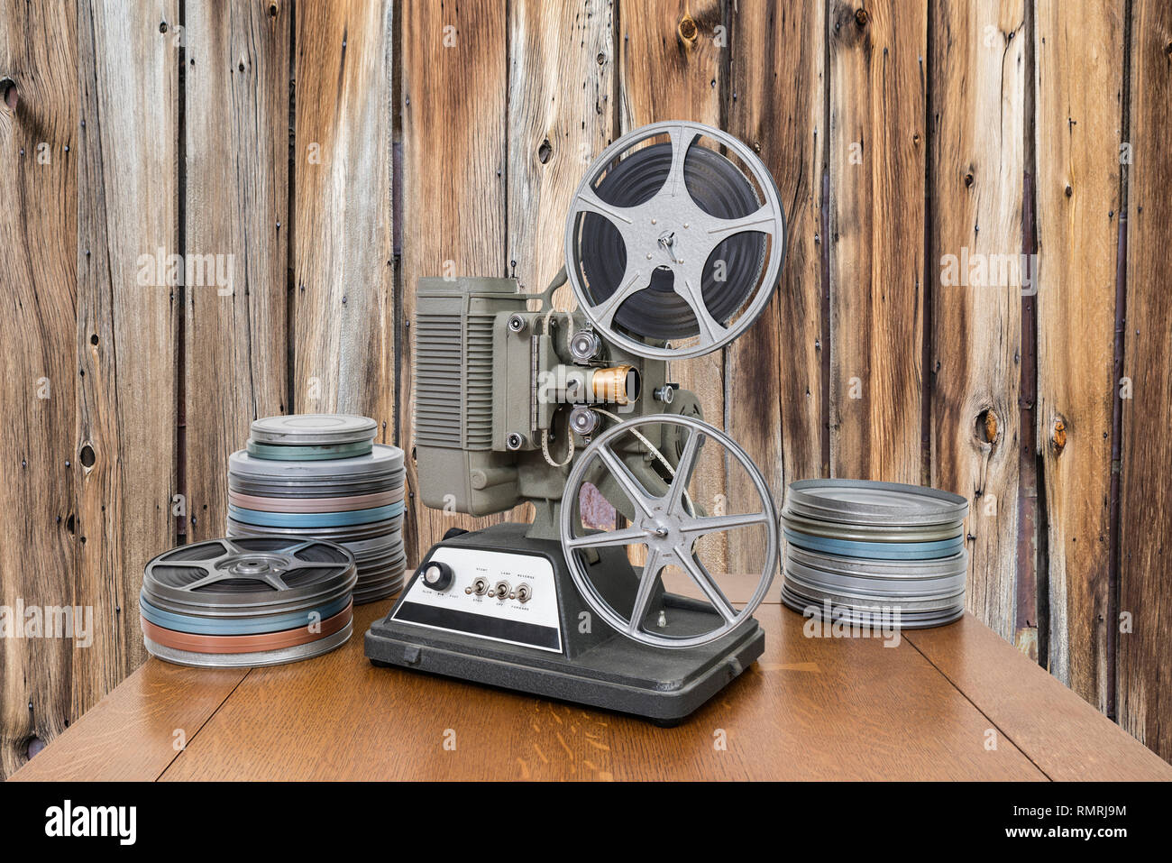 Vintage 8mm home movie projector and film cans with old wood wall. Stock Photo