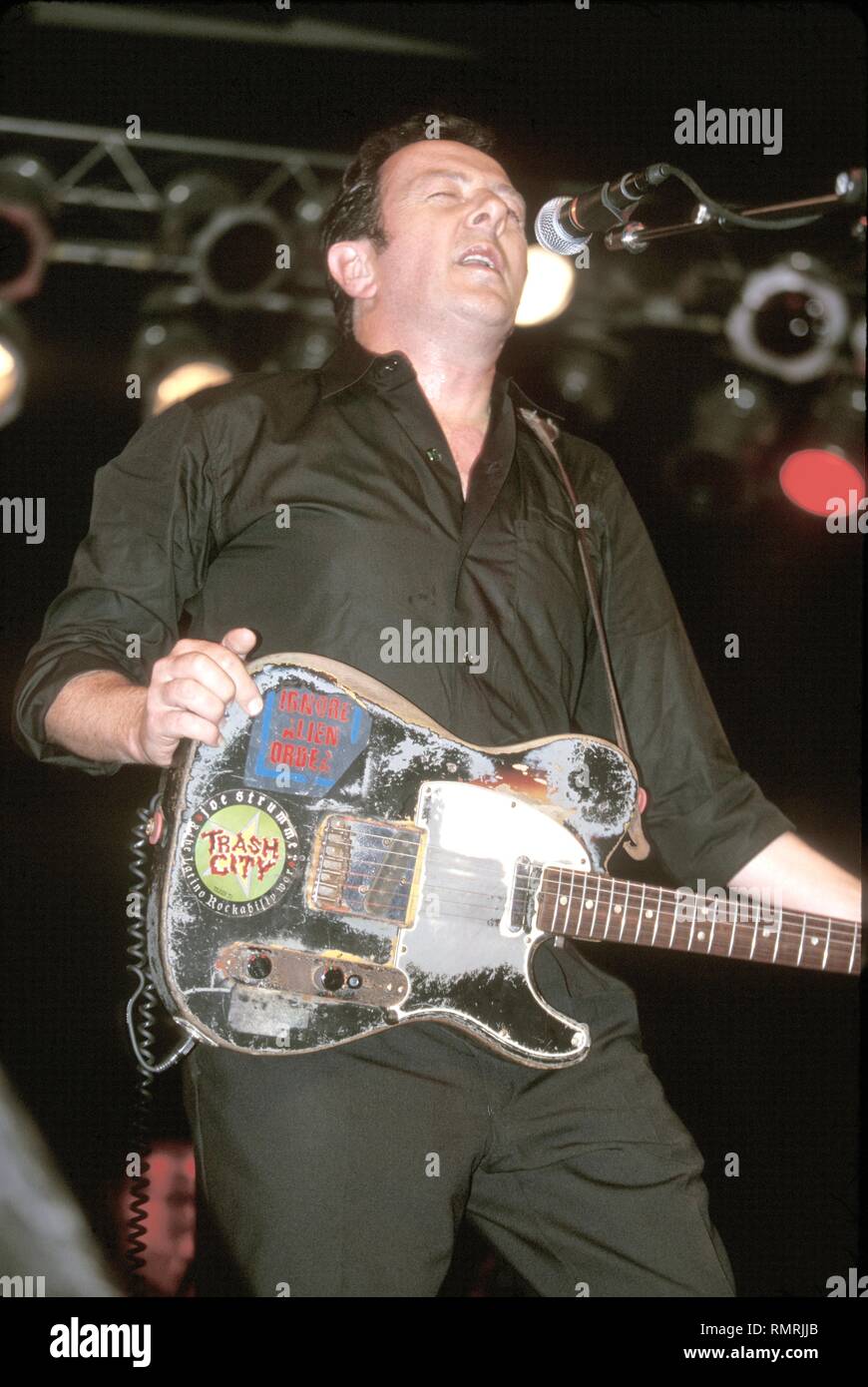 John Graham Mellor, better known by his stage name Joe Strummer, lyricist, rhythm guitarist and lead singer of the punk rock band The Clash, is shown performing on stage during a 'live' concert appearance with his solo band The Mescaleros. Stock Photo