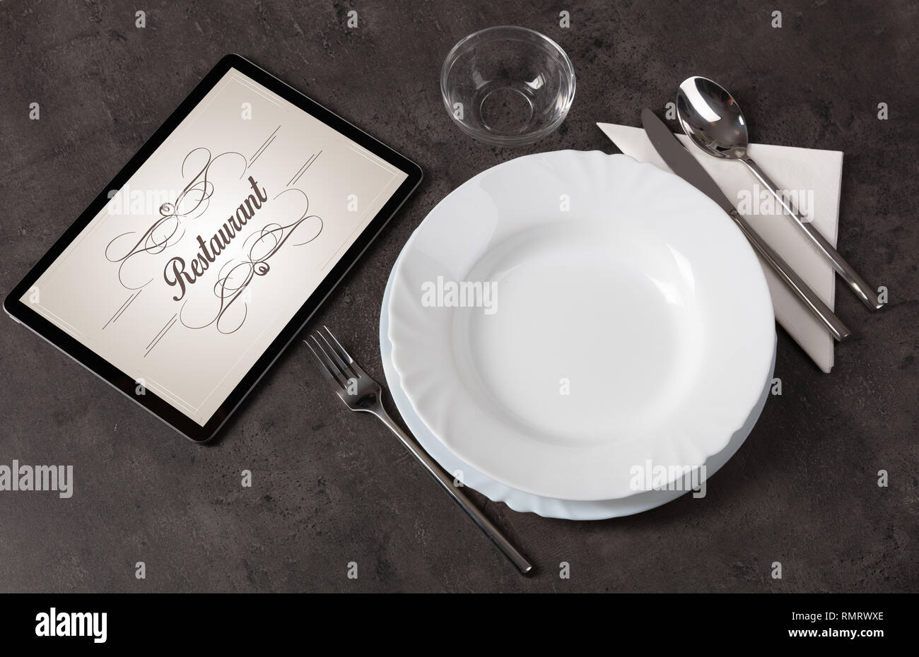 Tablet with stylish restaurant logo and laid table  Stock Photo