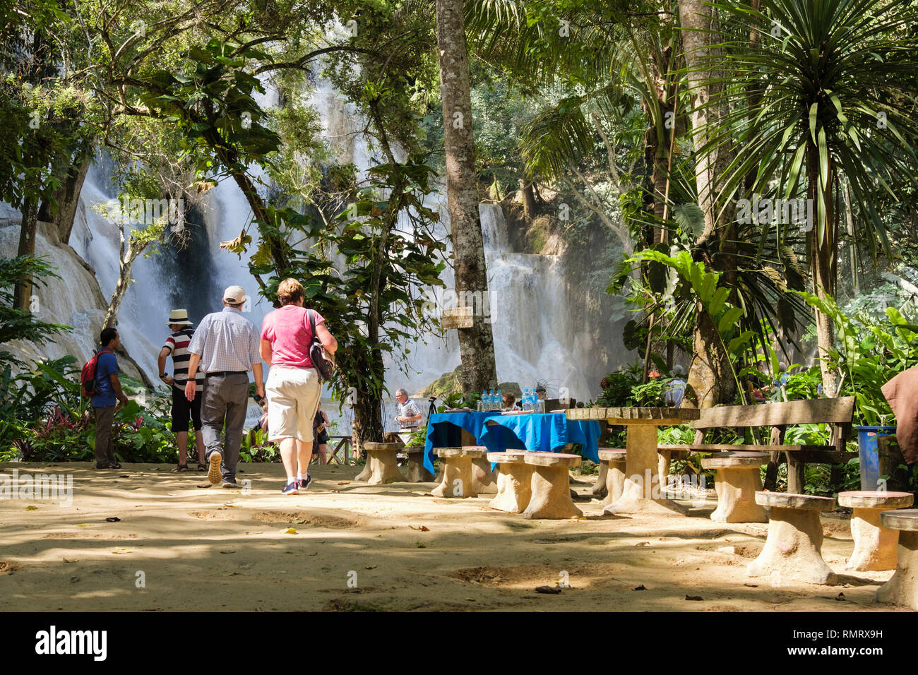Tourists and picnic tables near upper cascade at Tat Kuang Si waterfalls. Luang Prabang, Louangphabang province, Laos, southeast Asia Stock Photo