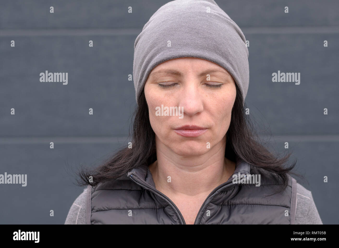 Portrait of Calm unemotional middle aged woman in gray beanie hat. Stock Photo