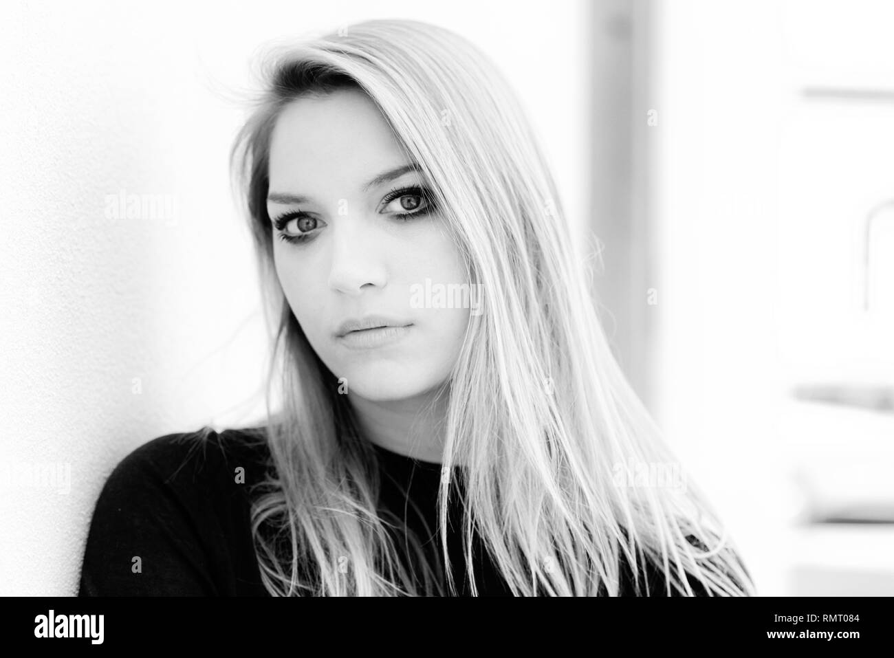Greyscale portrait of a gorgeous young woman with long blond hair looking thoughtfully at the camera with a quiet calm expression Stock Photo