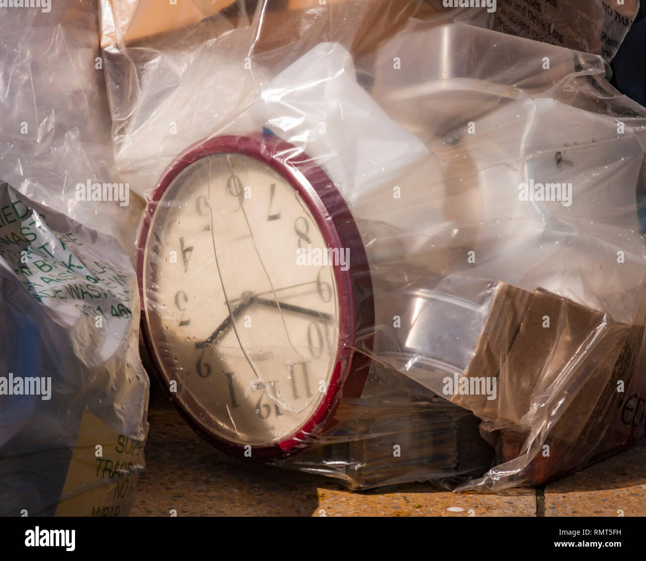 Edinburgh, Scotland - May 11 2015: A Waste of Time. Photograph showing an office clock inside plastic bags of rubbish stacked in a city street. Stock Photo