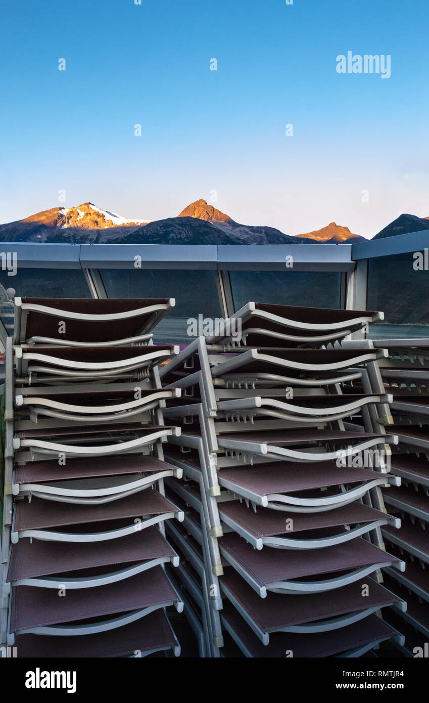 Stacked and secured lounge chairs on cruise ship outdoor deck with early morning sunrise light