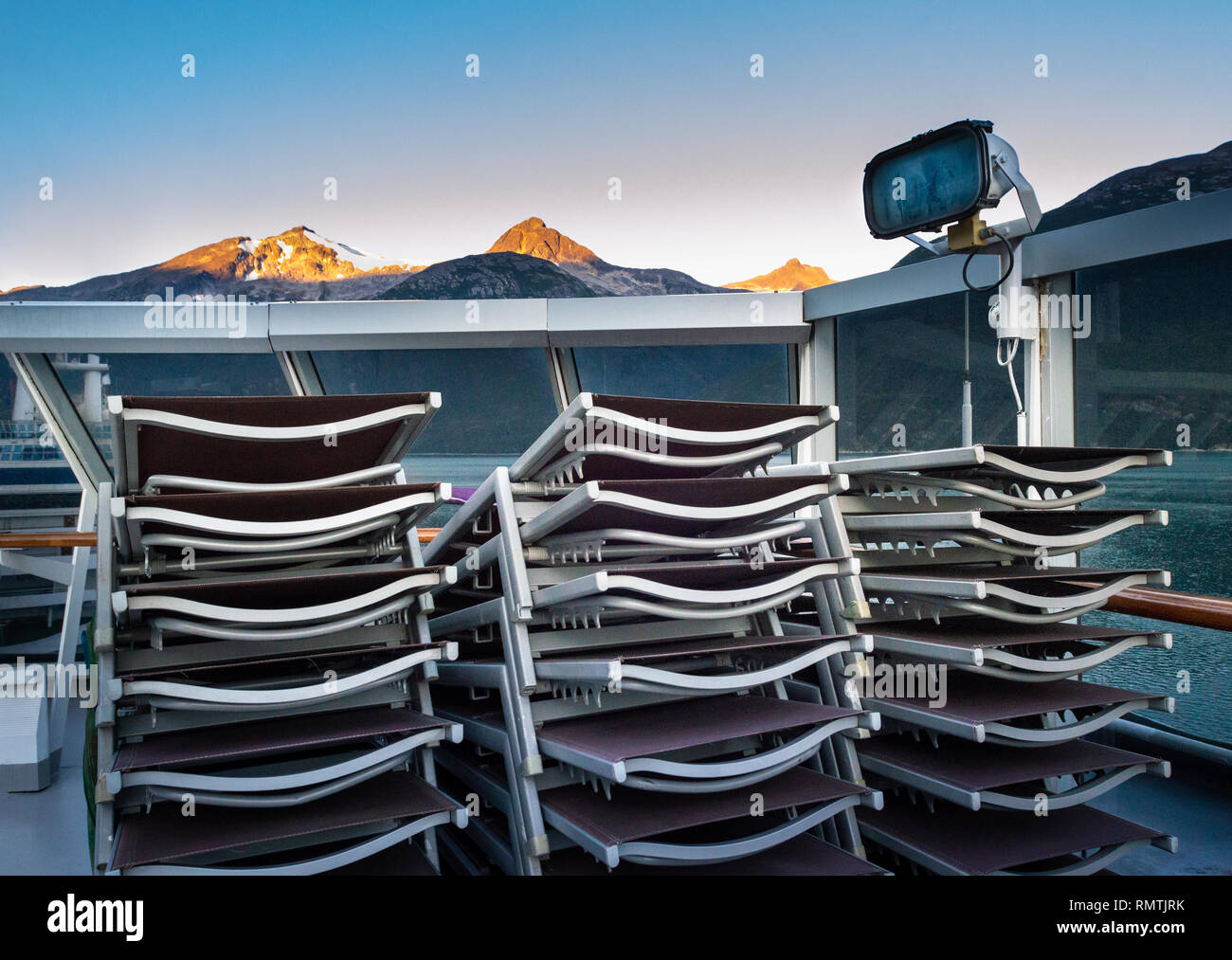 Stacked and secured lounge chairs on cruise ship outdoor deck with early morning sunrise light