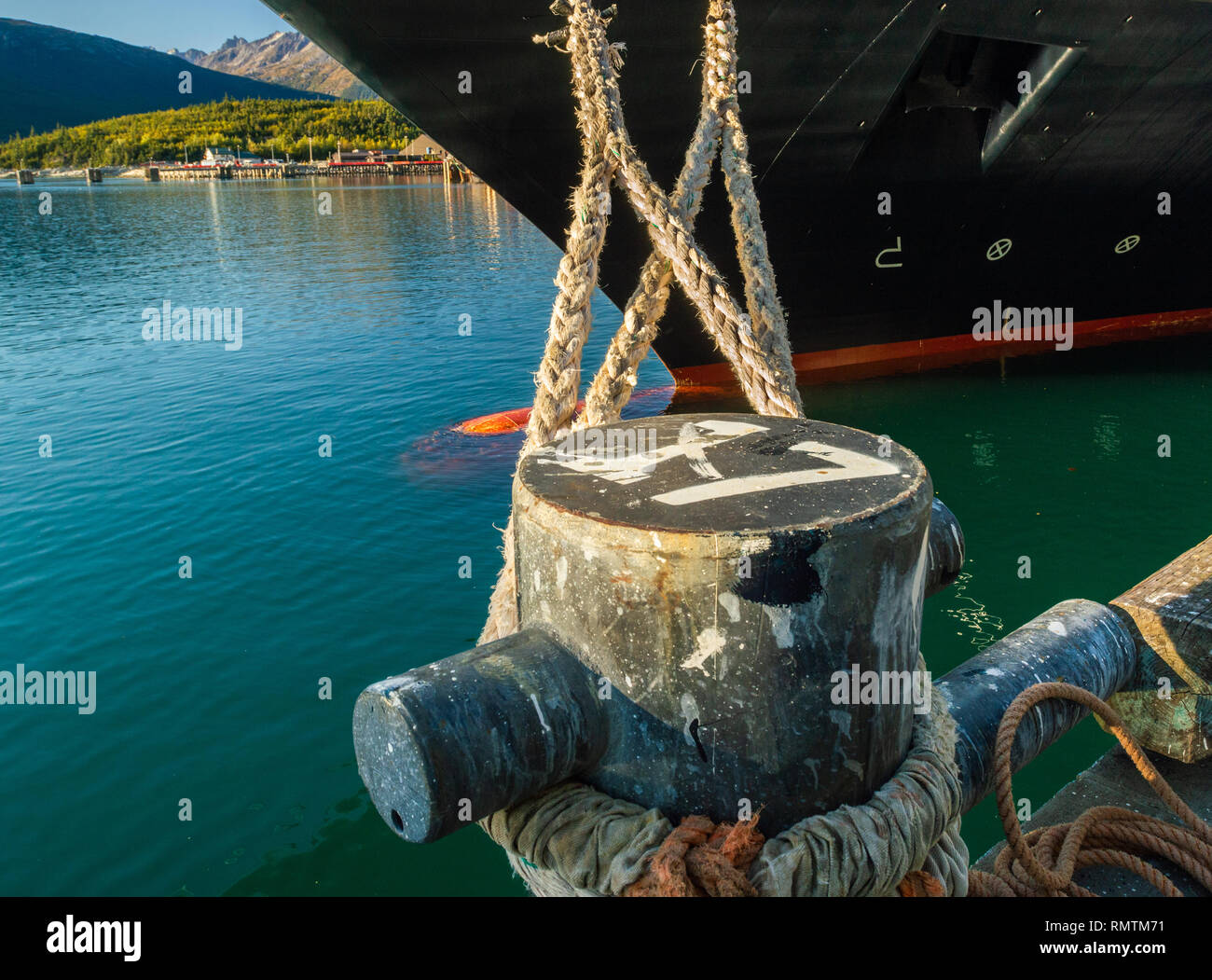 Mooring lines extending from bow of cruise ship, tied to bollard at