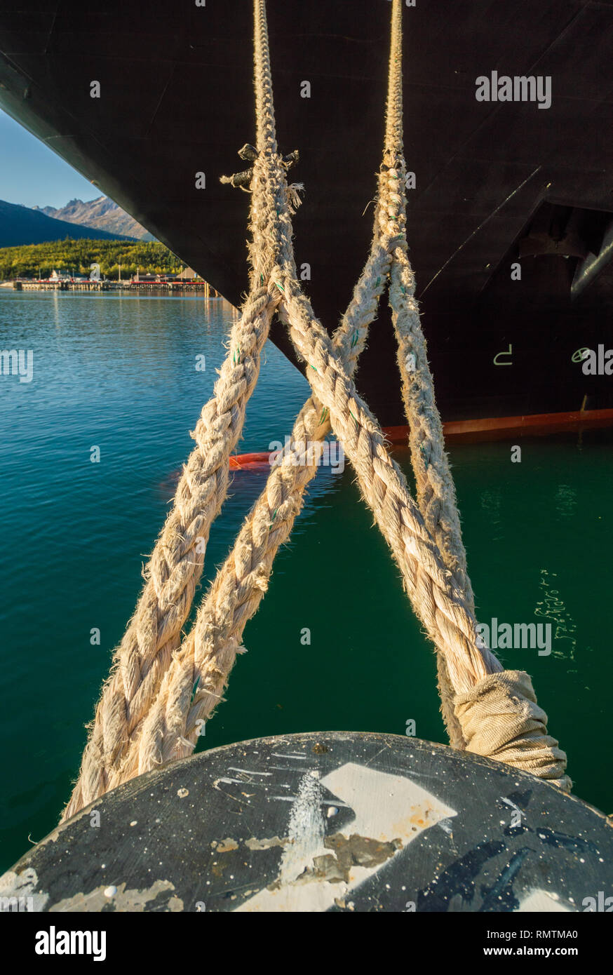 Mooring lines extending from bow of cruise ship, tied to bollard at