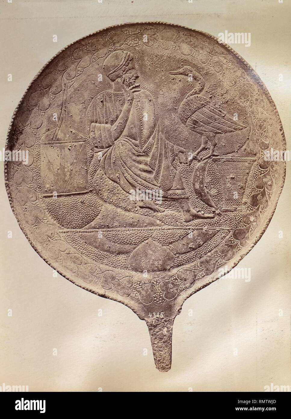 Dorso de un espejo de cobre con decoración de una figura femenina y un ave. Stock Photo