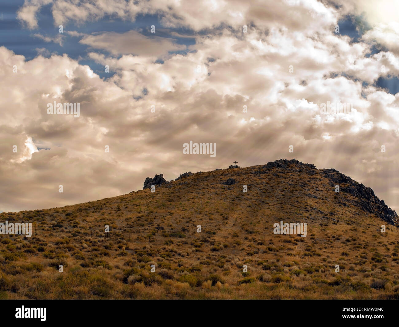 Religious cross on a sagebrush covered hill in the Nevada desert landscape photograph. Stock Photo