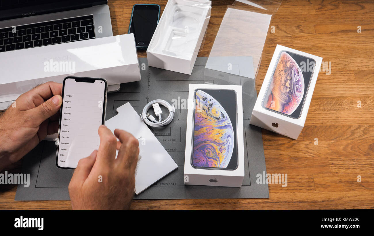 PARIS, FRANCE - SEPTEMBER 21, 2018: Apple fan boy unboxing latest new Apple Iphone Xs Max and Xs flagship smartphone mobile phone model from Apple Computers select language on display Stock Photo