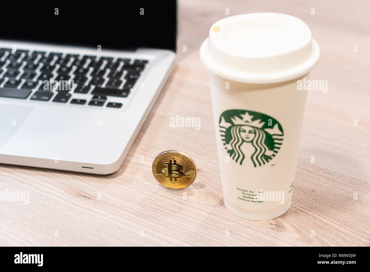 Cryptocurrency Bitcoin next to Starbucks coffee cup. In the office next to  computer laptop. Slovenia 13.02.2019 Stock Photo - Alamy