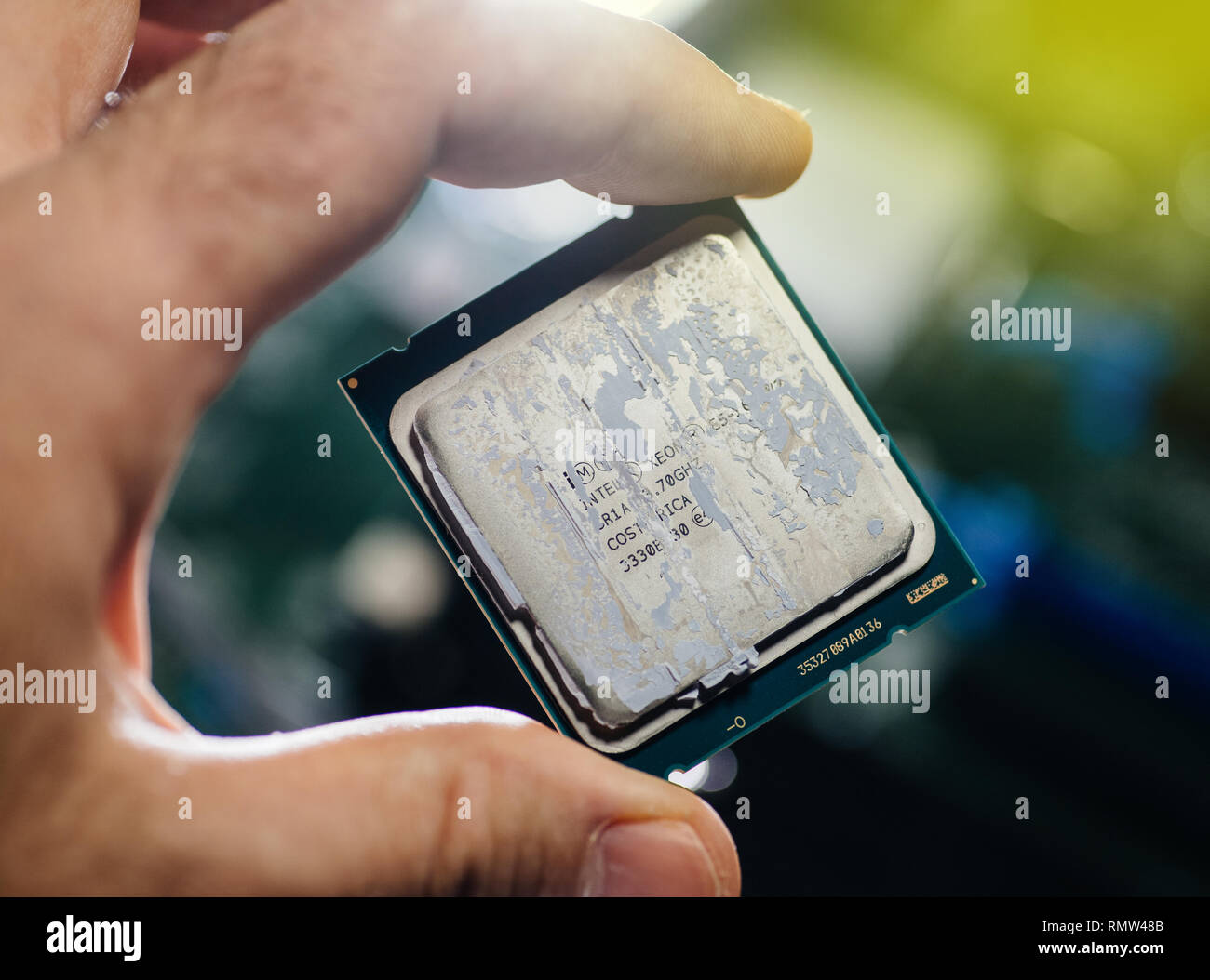 London, United Kingdom - Feb 5, 2019: Man hand IT engineer holding against technological motherboard background new Intel Xeon professional CPU processor Broadwell FCLGA2011-3 Stock Photo