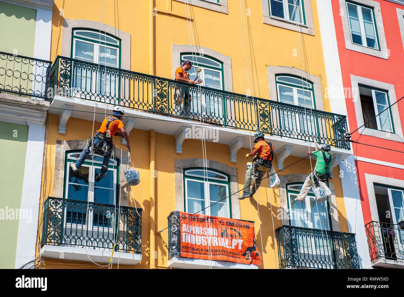 Painters hanging from ropes while working on a building in Principe Real, Lisbon, Portugal. Stock Photo