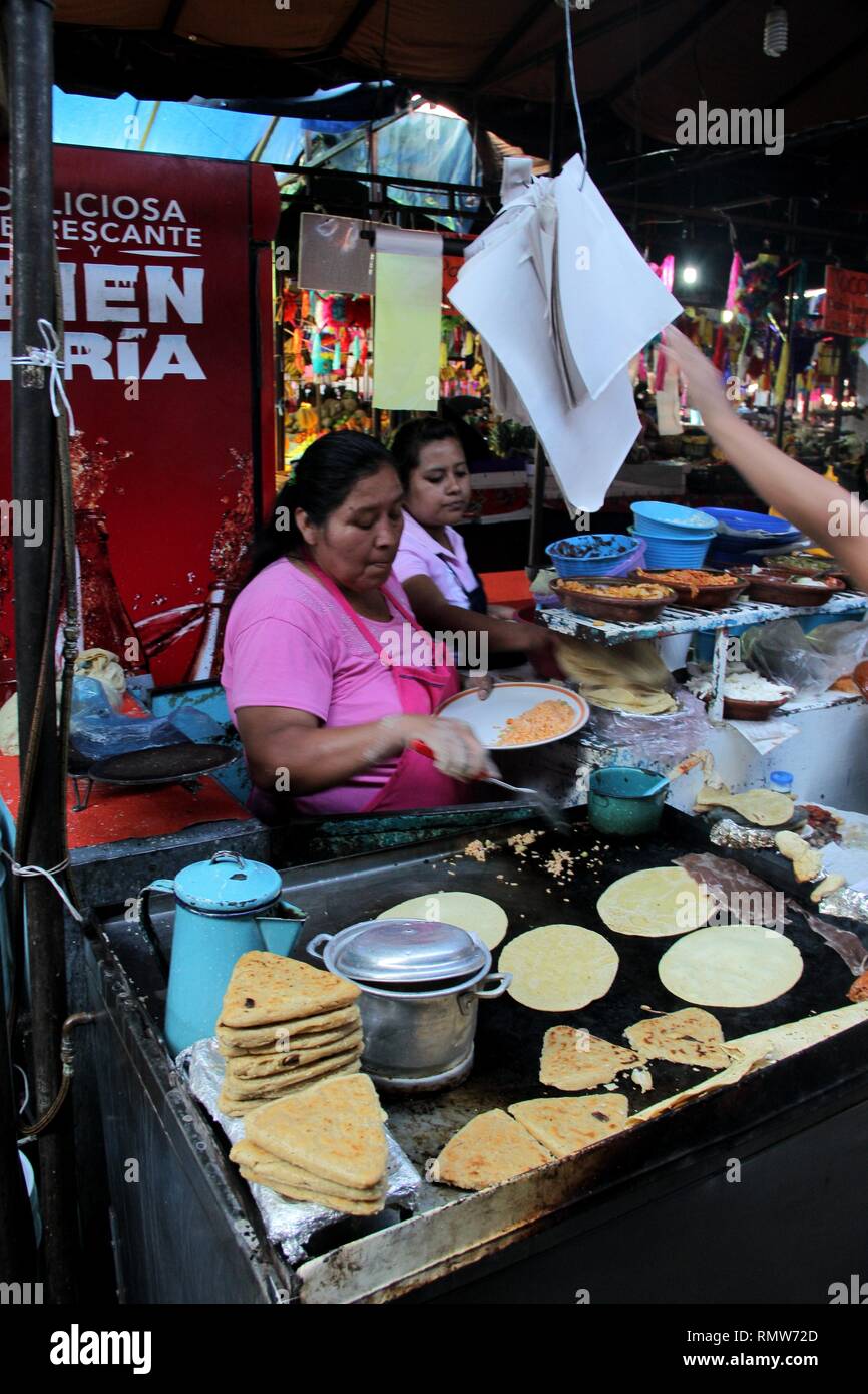 Mexican women cooking mexican food tacos and huaraches in the market. Stock Photo