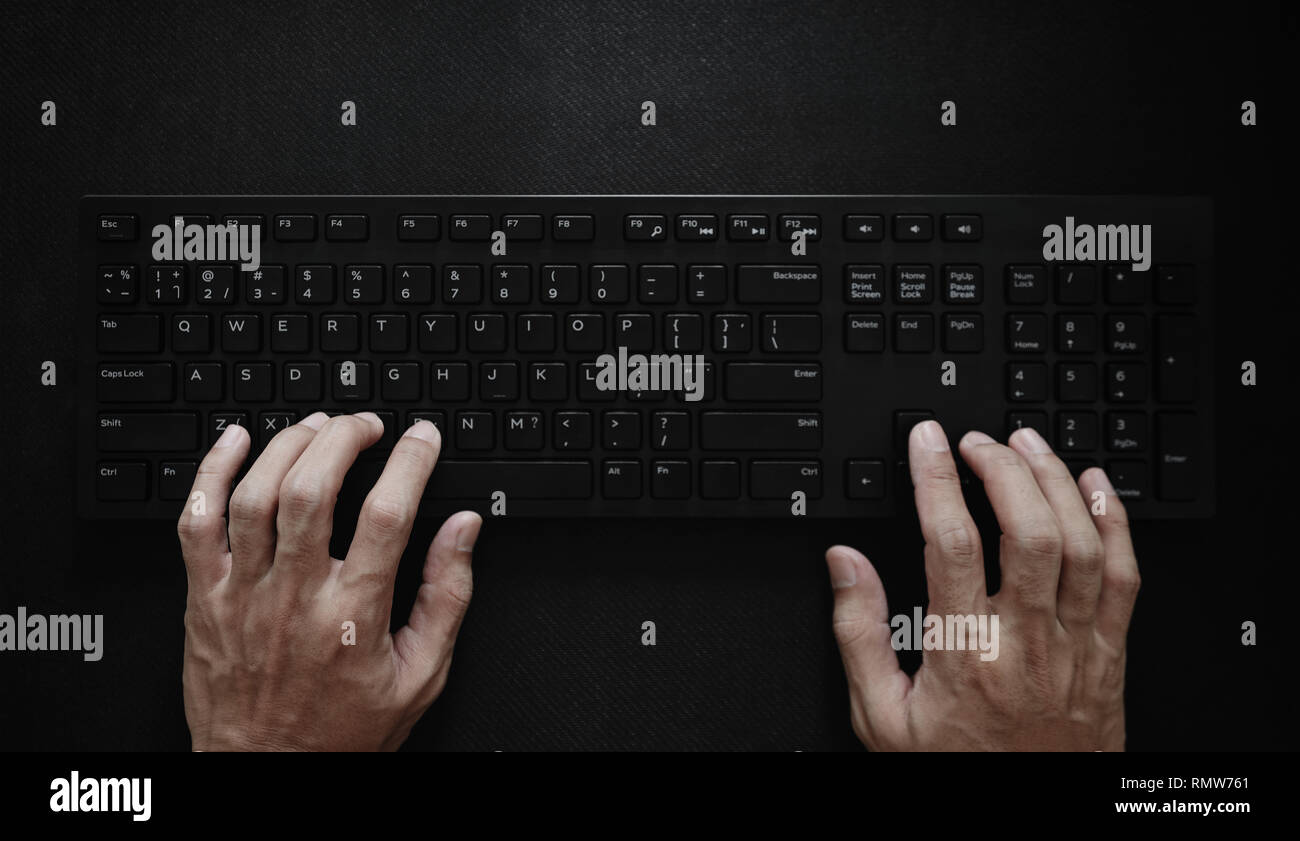 Top view, Hand typing computer keyboard on black background Stock Photo