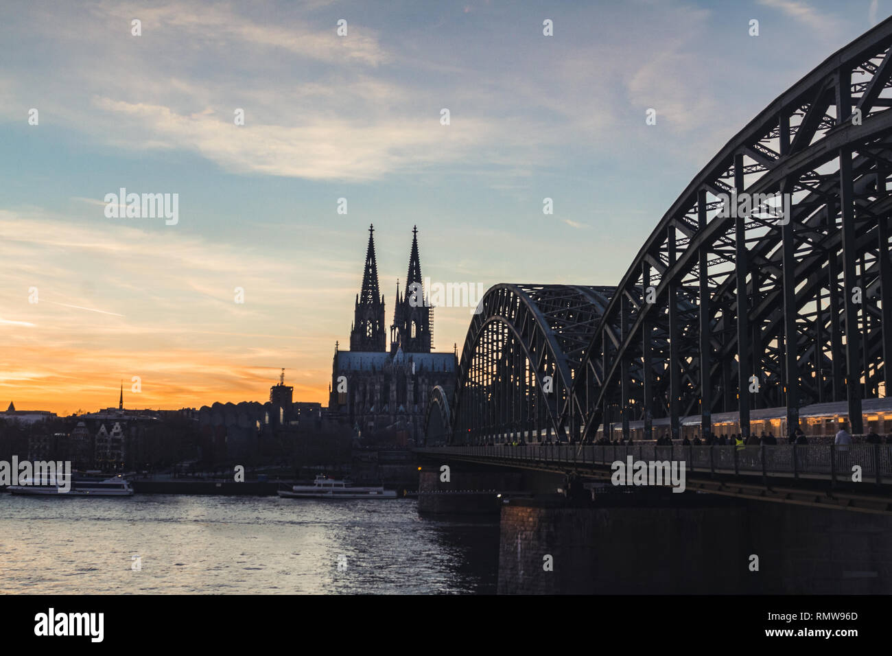 Cologne skyline with Cologne Cathedral and Hohenzollern bridge at sunset with cloudy sky Stock Photo